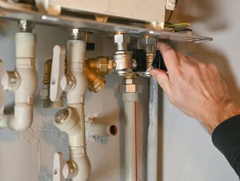 Hand turning a brass shut-off valve on water supply lines